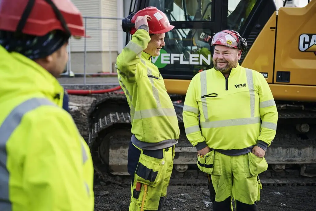 Bildet viser ansatte hos Veflen Entreprenør som smiler og snakker sammen