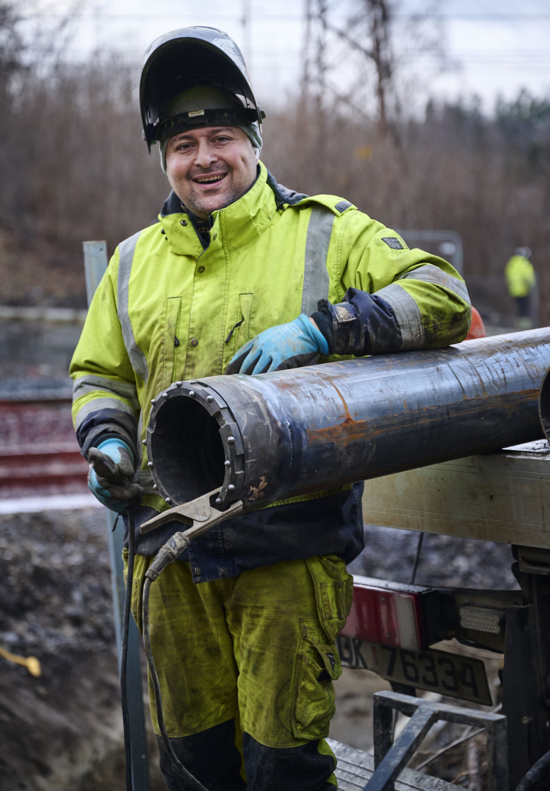 Bildet viser en ansatt hos Veflen Entreprenør som smiler med arbeidsklær