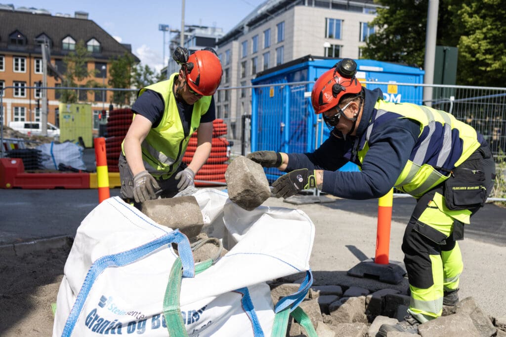 Camilla Dokken, lastebilsjåfør hos Veflen bidrar også der det er behov. Her løfter hun brostein.